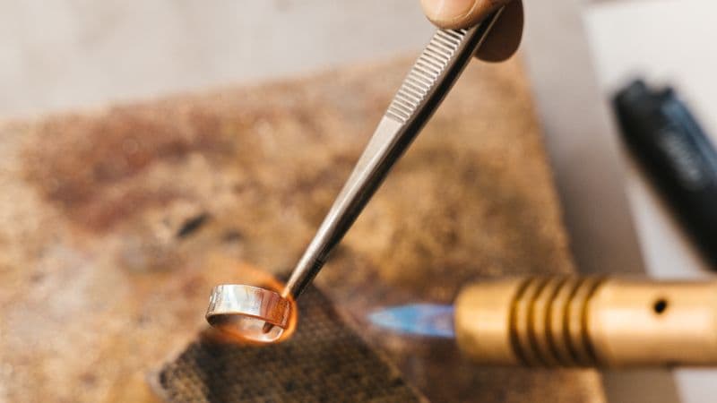 Goldsmith soldering a ring at a jewellery workbench